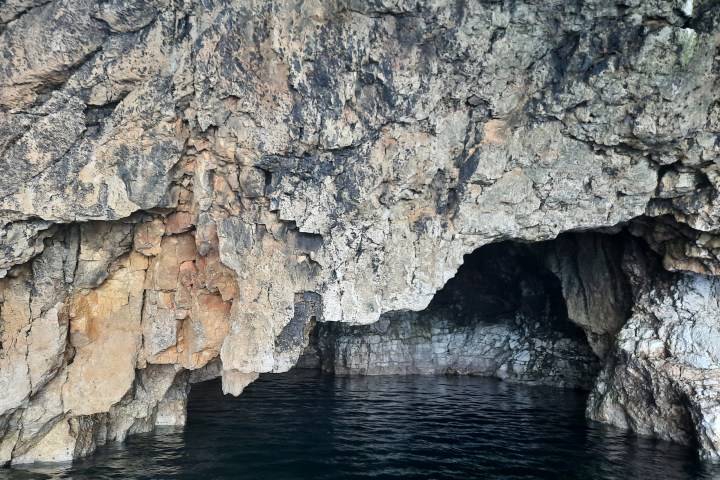 Rocky cave entrance by dark water
