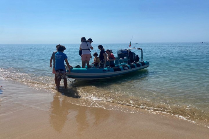 People on a small motorboat near the shore on a sunny day.